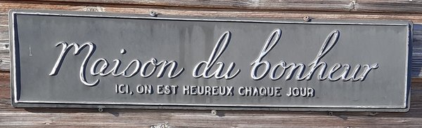 Ein Bild zeigt ein Schild mit Maison du bonheur